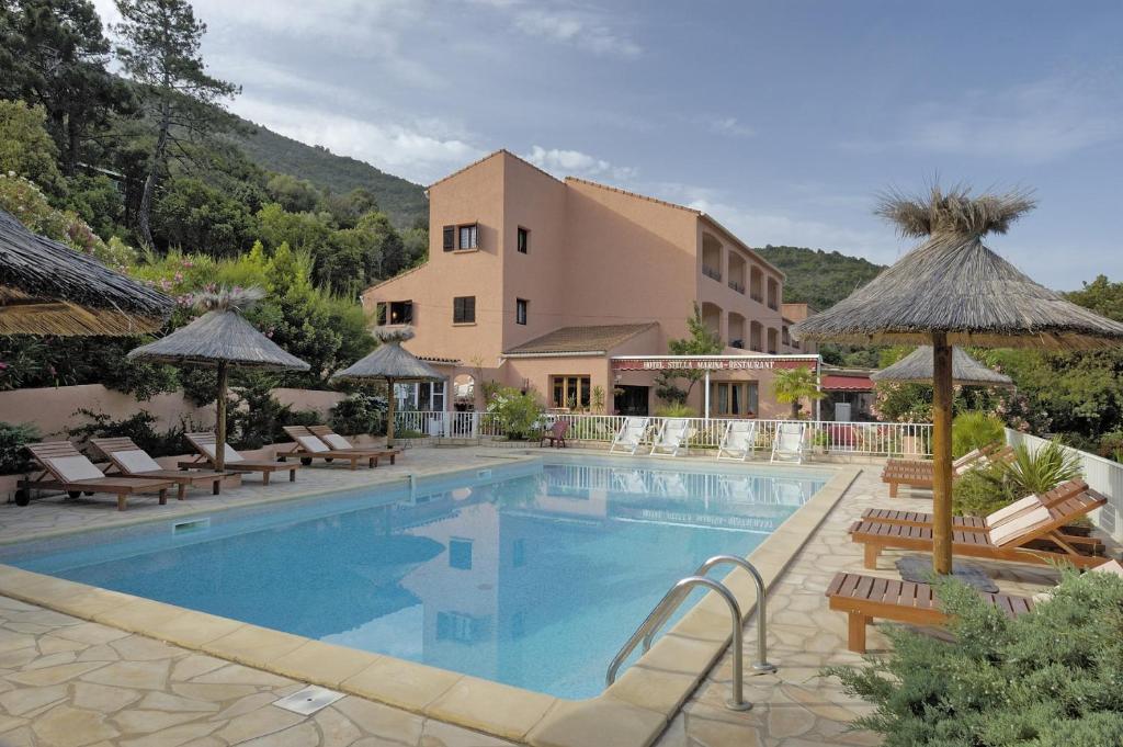 塞雷拉Hotel Stella Marina的一座带椅子和遮阳伞的游泳池位于一座建筑旁边