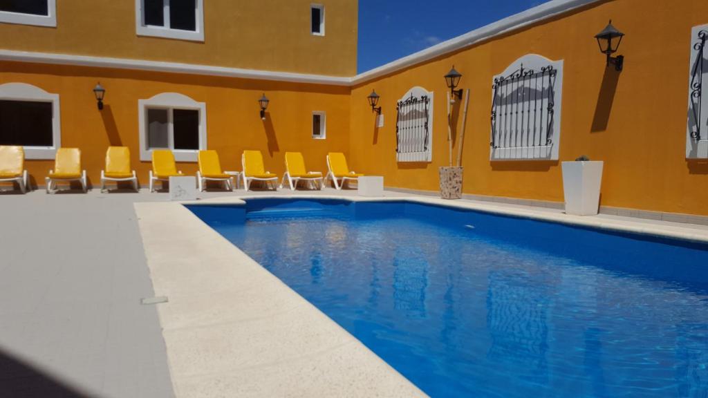 拉斯格路塔斯Hotel Colonos的一座游泳池,位于一座拥有黄色墙壁和黄色椅子的建筑中