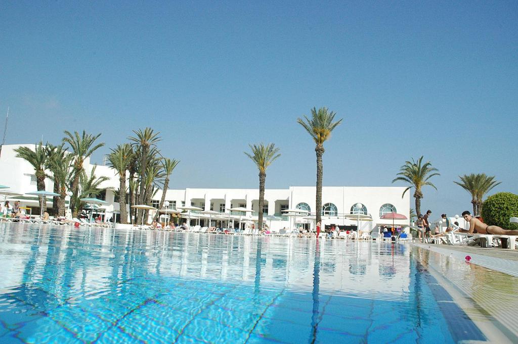 甘达坞伊港坎托维埃尔默拉蒂俱乐部酒店的一座棕榈树大型游泳池和一座建筑