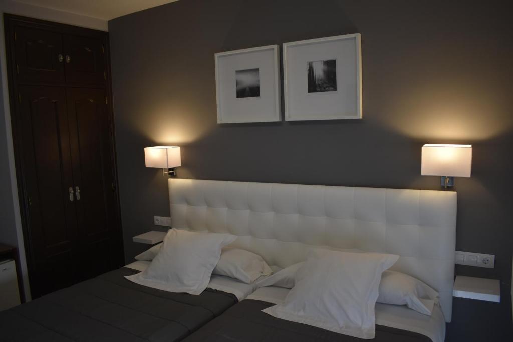 哈拉马河畔帕拉库埃略斯埃尔罗西奥旅馆的一间卧室配有一张带两盏灯的大型白色床。