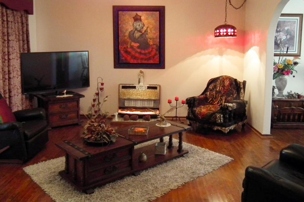 珀斯The Spanish Guesthouse, pets considered的客厅配有电视、椅子和桌子