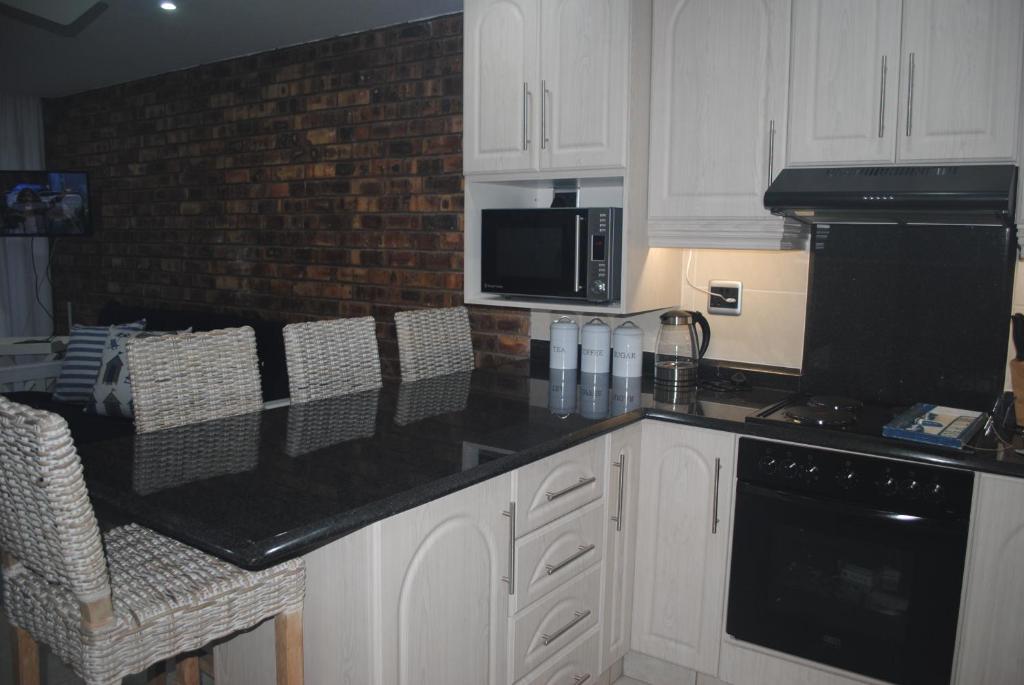 斯科特堡11 Coral Sands的厨房配有白色橱柜和黑色台面