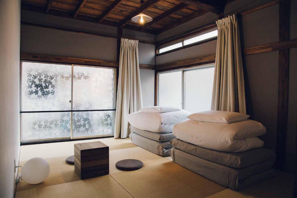 东京hanare的一间设有窗户的客房内的卧室,配有两把脚凳