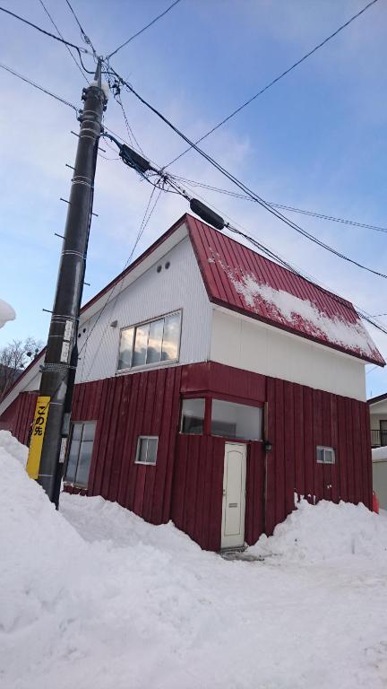 富良野雪山木屋公寓的雪中有一根杆的红白建筑
