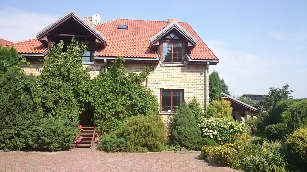 凯卡瓦自治市Mētrini apartment near river Daugava的一座有红色屋顶和灌木的房子