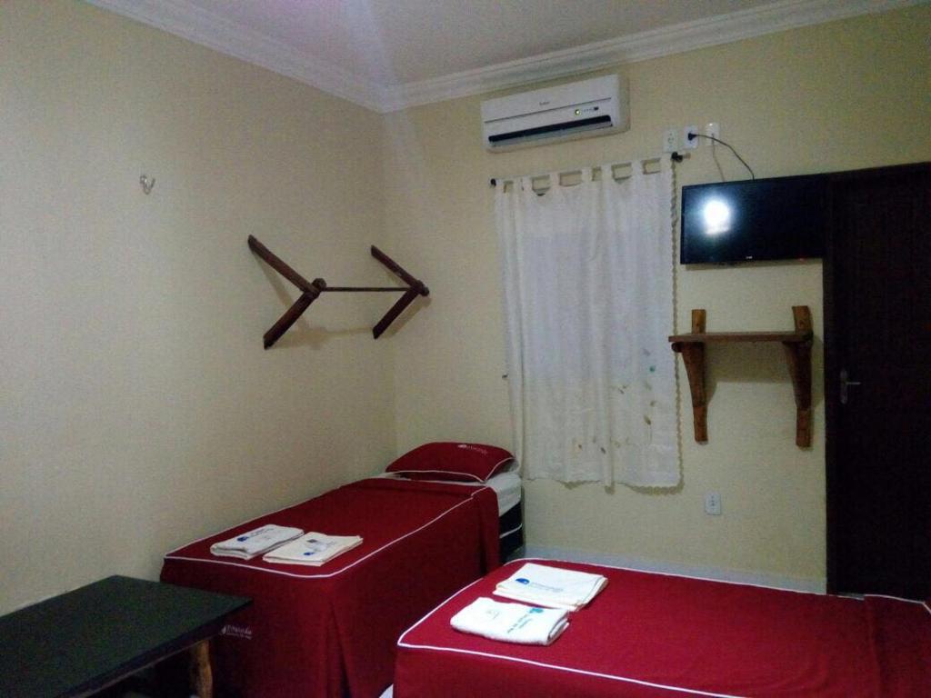 索布拉尔Pousada Aquino的一间房间,房间内设有两张红色的床