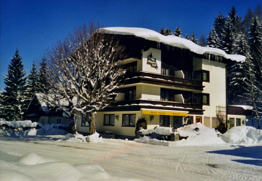 安纳贝格-伦格茨阿尔彭霍夫安娜贝格酒店的一座有雪覆盖的建筑,前面有一棵树