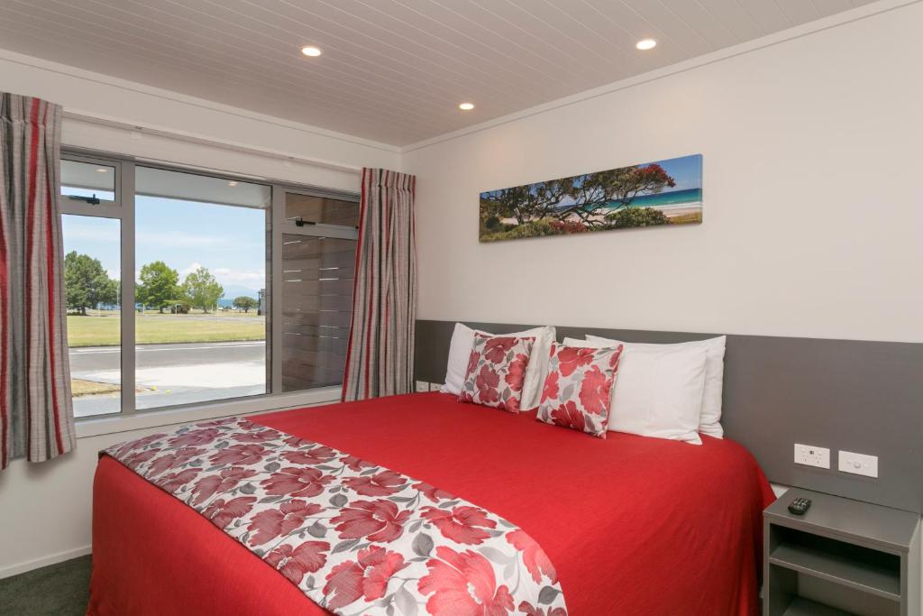 陶波e汽车旅馆的一间卧室设有红色的床和窗户。