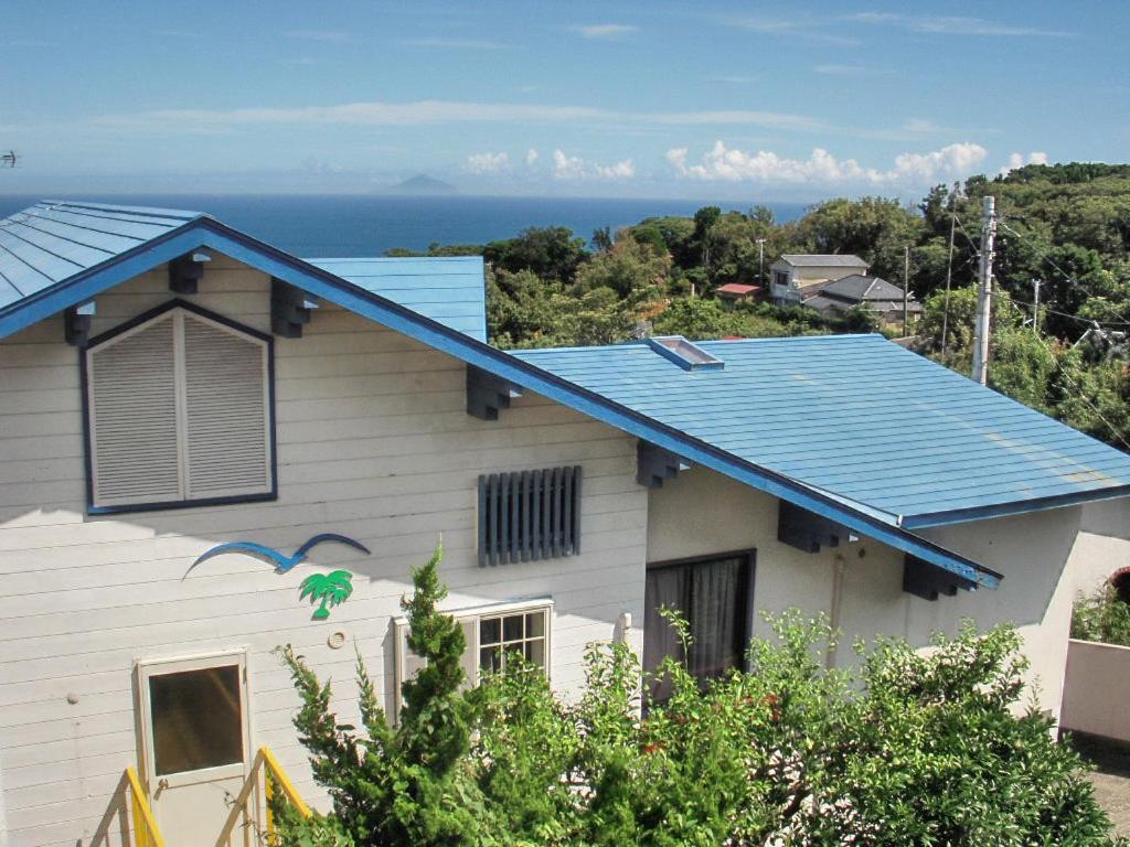 下田逸舒塔图旅馆的蓝色屋顶的房子,背景是大海