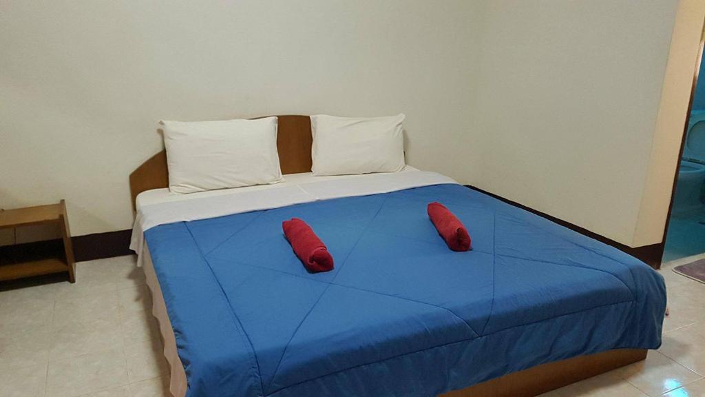 色军LP公寓式酒店的一张蓝色的床,上面有两个红色的枕头