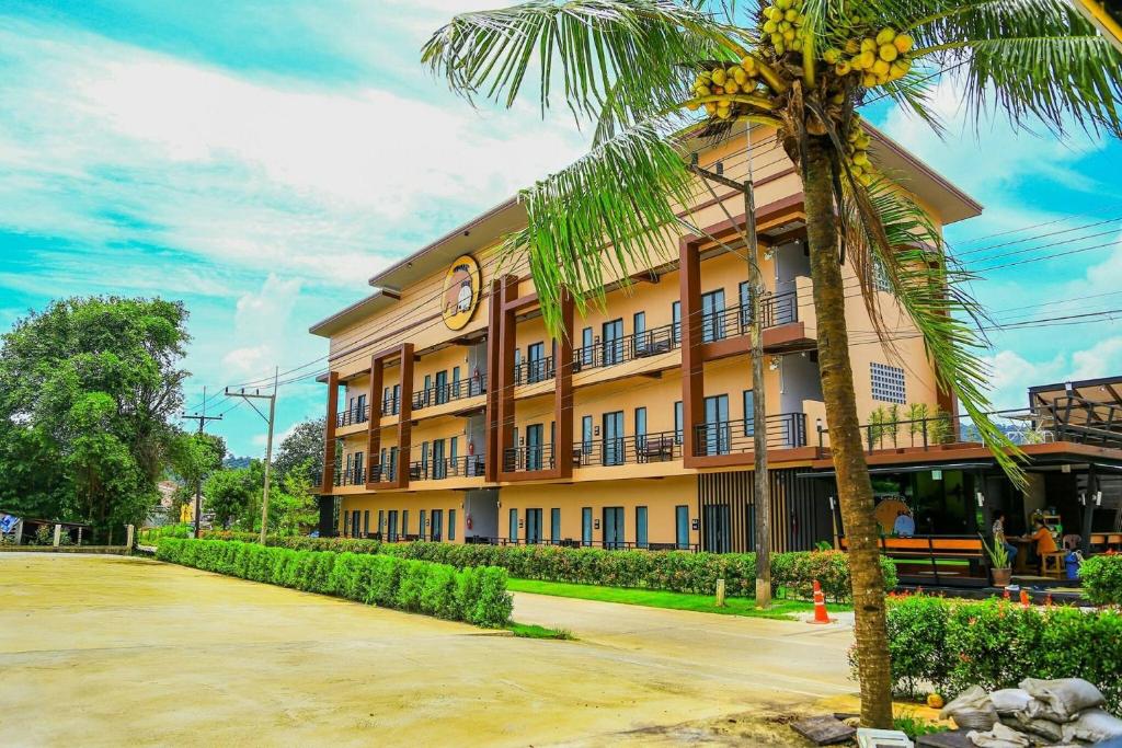 拉廊The Ele Hotel Ranong - SHA Extra Plus的前面有棕榈树的建筑