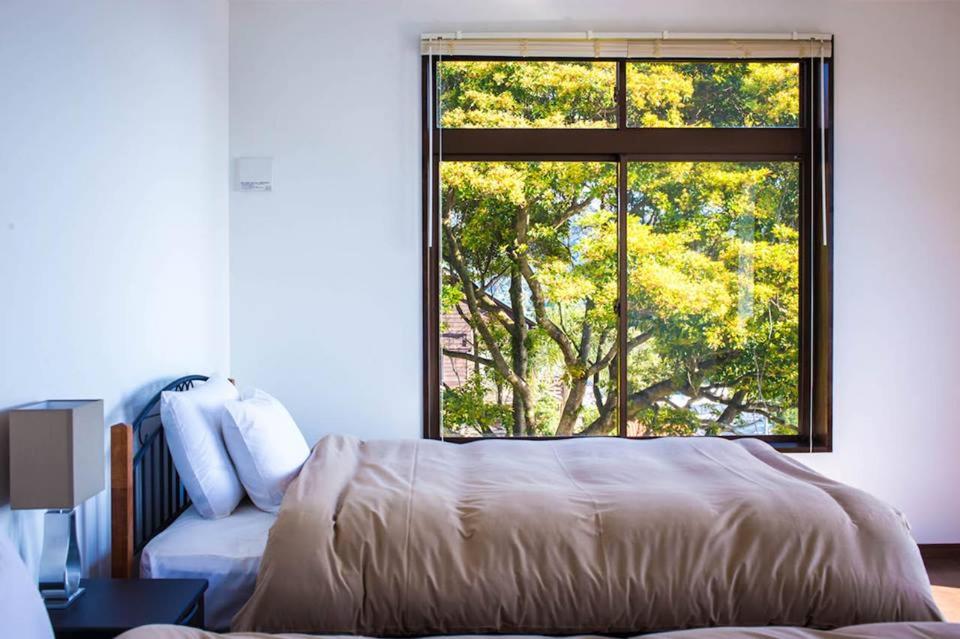 宫崎小花园旅馆的一间卧室设有一张床和一个大窗户