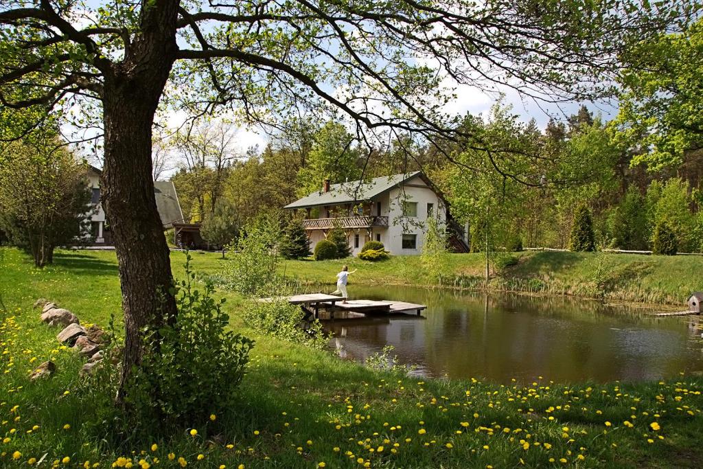 SmolarniaSmolarnia的站在野餐桌上,站在房子前面的池塘边的人