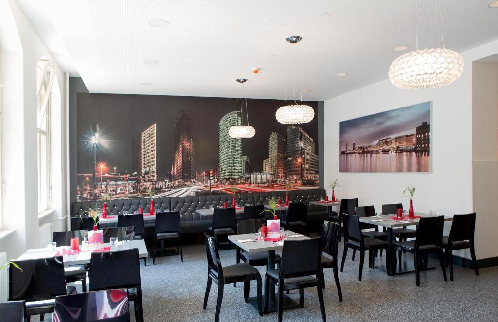 柏林柏林东十字青年旅馆的一间配备有桌椅的用餐室,并画有城市的画作