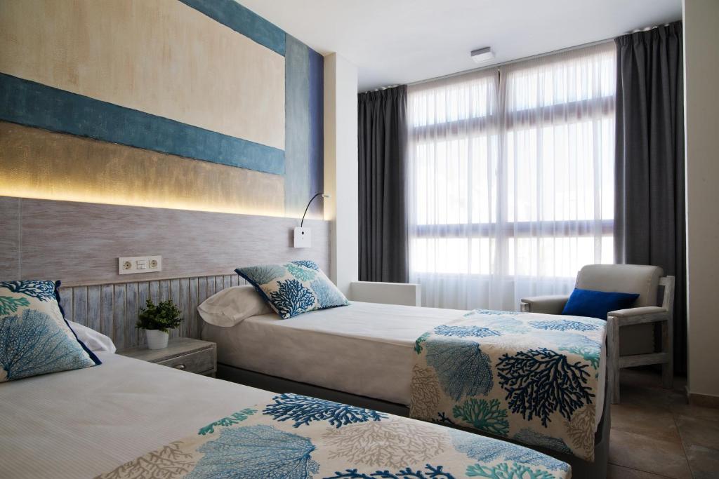 大加那利岛拉斯帕尔马斯ApartHotel Idafe的酒店客房设有两张床和窗户。