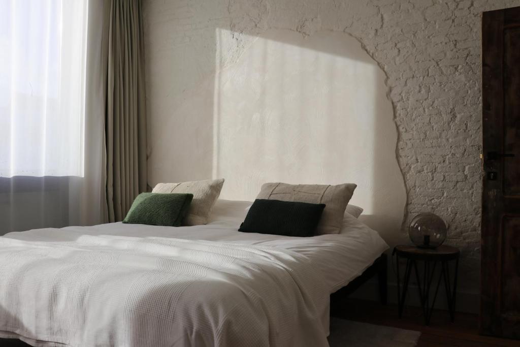 安特卫普Mañana Mañana的卧室配有白色床和2个绿色枕头