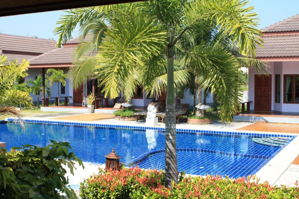 盼武里河畔度假酒店的游泳池前的棕榈树