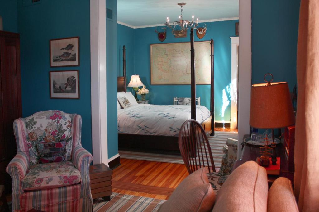 夏洛茨维尔Inn at Court Square的卧室拥有蓝色的墙壁,配有一张床和椅子