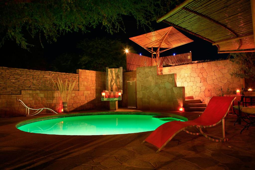 圣佩德罗·德·阿塔卡马基马尔酒店的夜间带红色椅子的小型游泳池