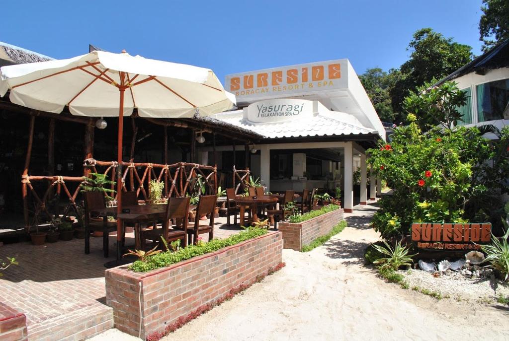 长滩岛Surfside Boracay Resort的一间带桌椅和遮阳伞的餐厅