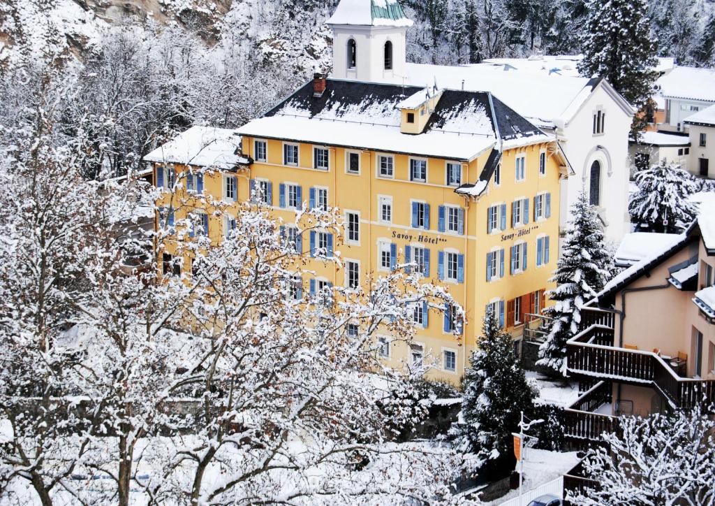 布里德莱班Savoy Hôtel的一座黄色的建筑,被积雪覆盖在城镇