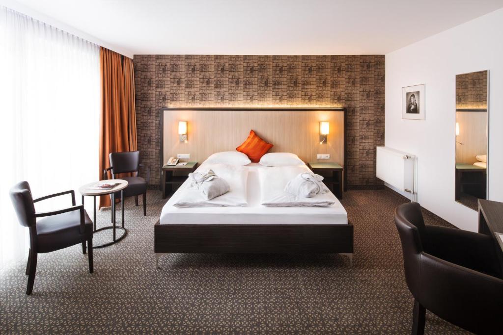 杜伊斯堡广场酒店 的酒店客房,配有一张床、一张桌子和椅子