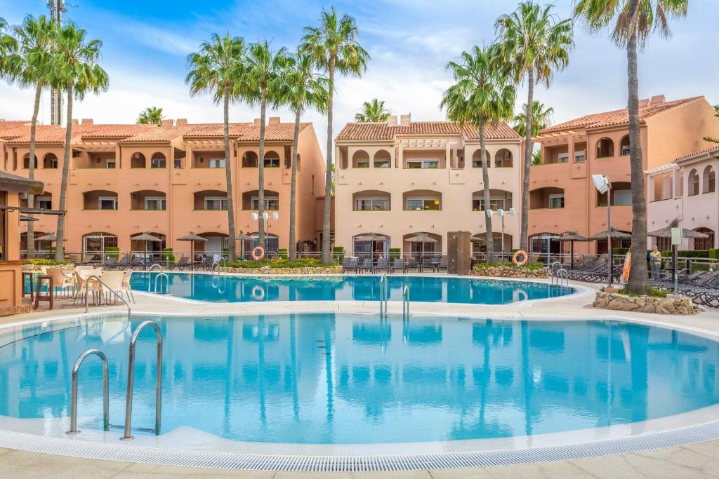 卡拉德米哈斯洛斯阿米戈斯海滩俱乐部钻石度假酒店的一座楼前棕榈树的大型游泳池