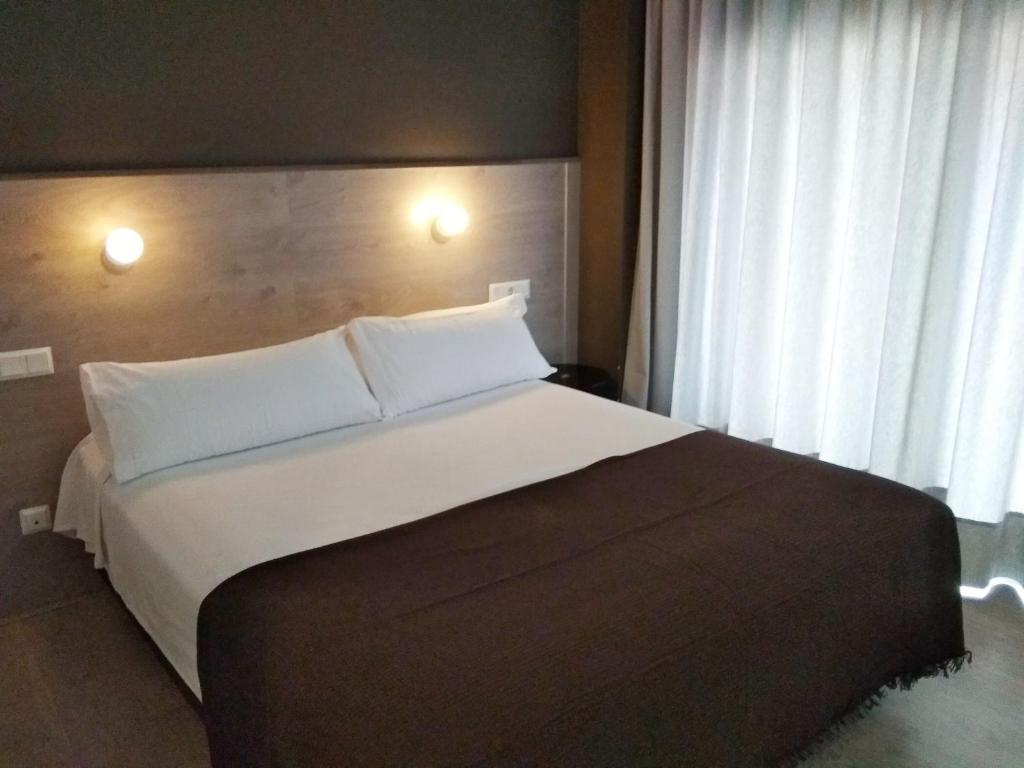 萨拉戈萨Hotel Delicias的卧室配有带白色枕头的大床