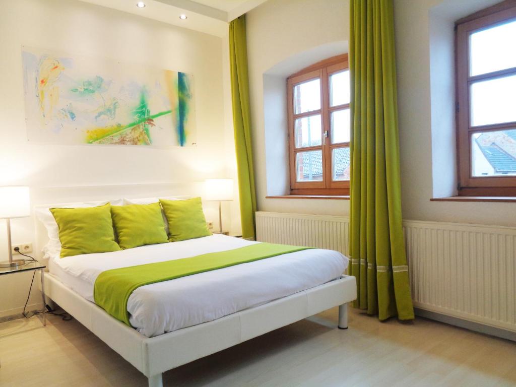 EimerslebenHotel Apartment Puell的一间卧室配有一张带绿色床单的床和窗户。