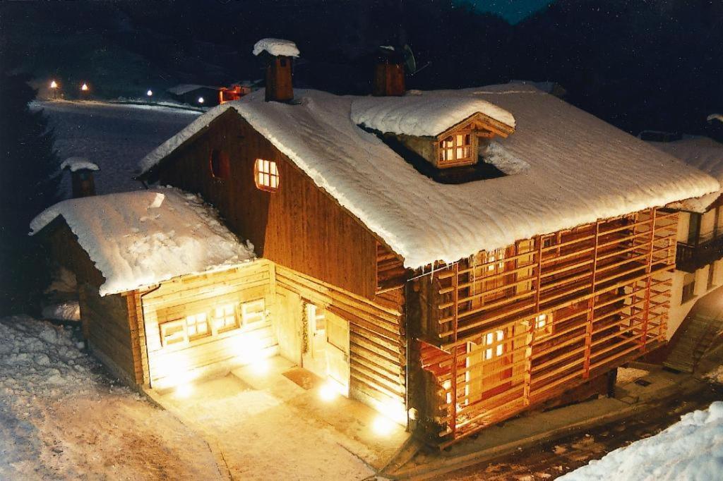 绍里斯Hotel Garni Plueme的木屋在晚上被雪覆盖