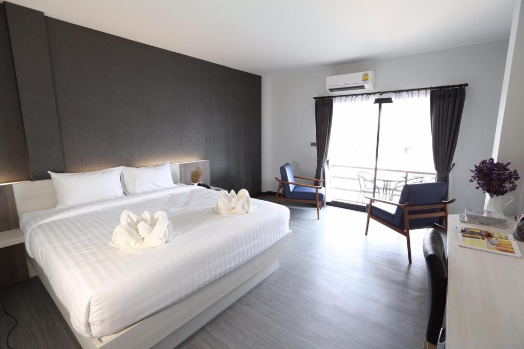 Nang Rong非常酷炫大酒店的卧室配有白色的床,上面有两朵白色的花