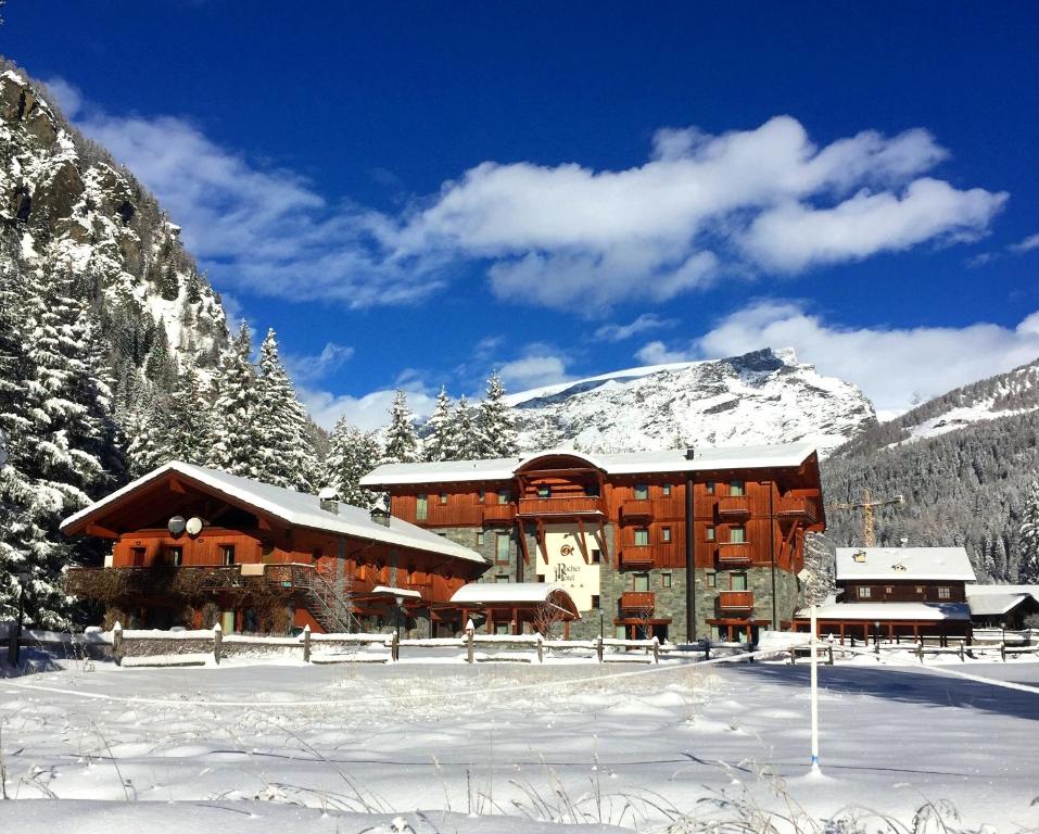 尚波吕克乐罗酒店的雪中一座大建筑,有雪覆盖的群山