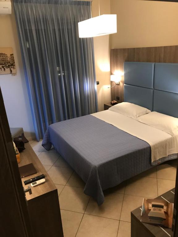 那不勒斯那不勒斯肯姆艾拉酒店的一间卧室配有床和蓝色窗帘