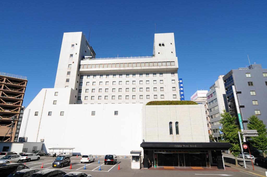 新泻新泻东映酒店的一座白色的大建筑,汽车停在停车场
