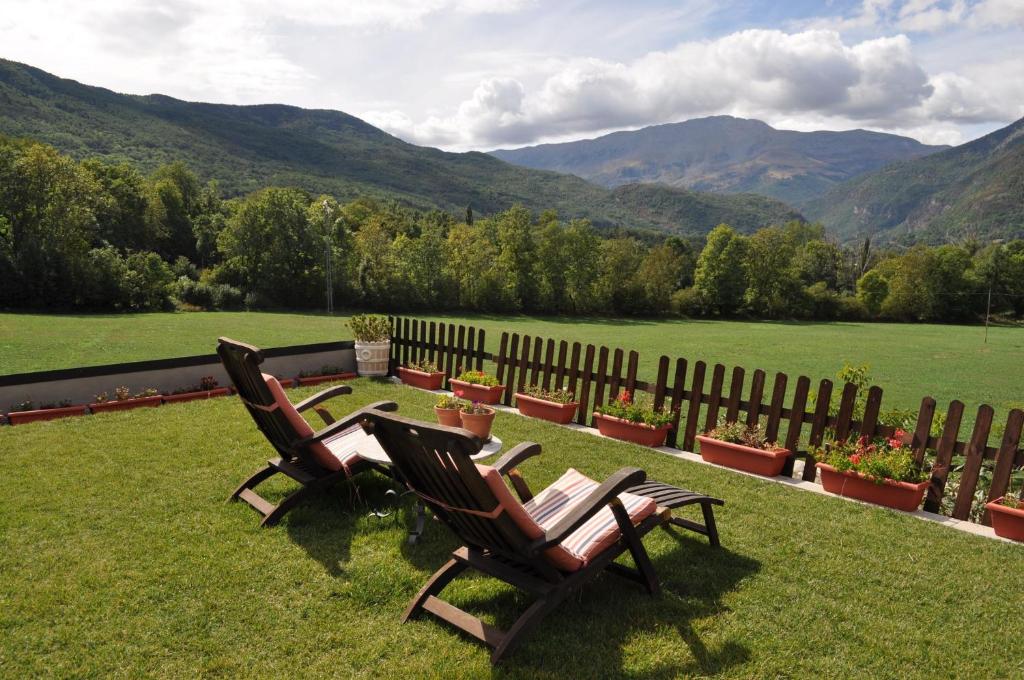 贝纳斯克塞尔瓦安希尔斯酒店的两把椅子坐在草坪上,背靠山