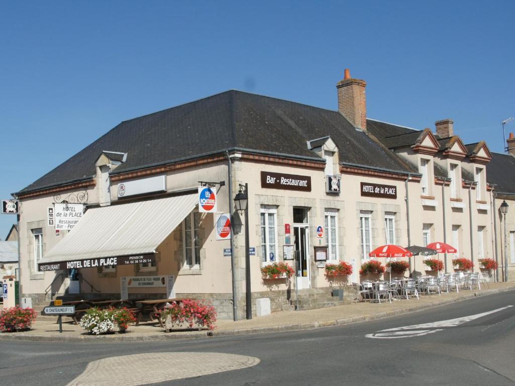 Germigny-des-PrésHôtel de la Place的街道上一座带桌椅的大型白色建筑