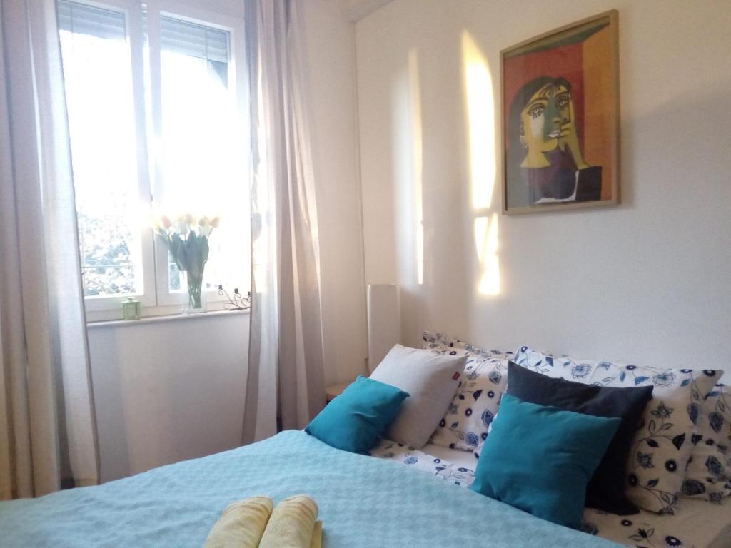 斯普利特Apartment Optimist/City Break的一间卧室配有一张带蓝色枕头的床和一扇窗户。