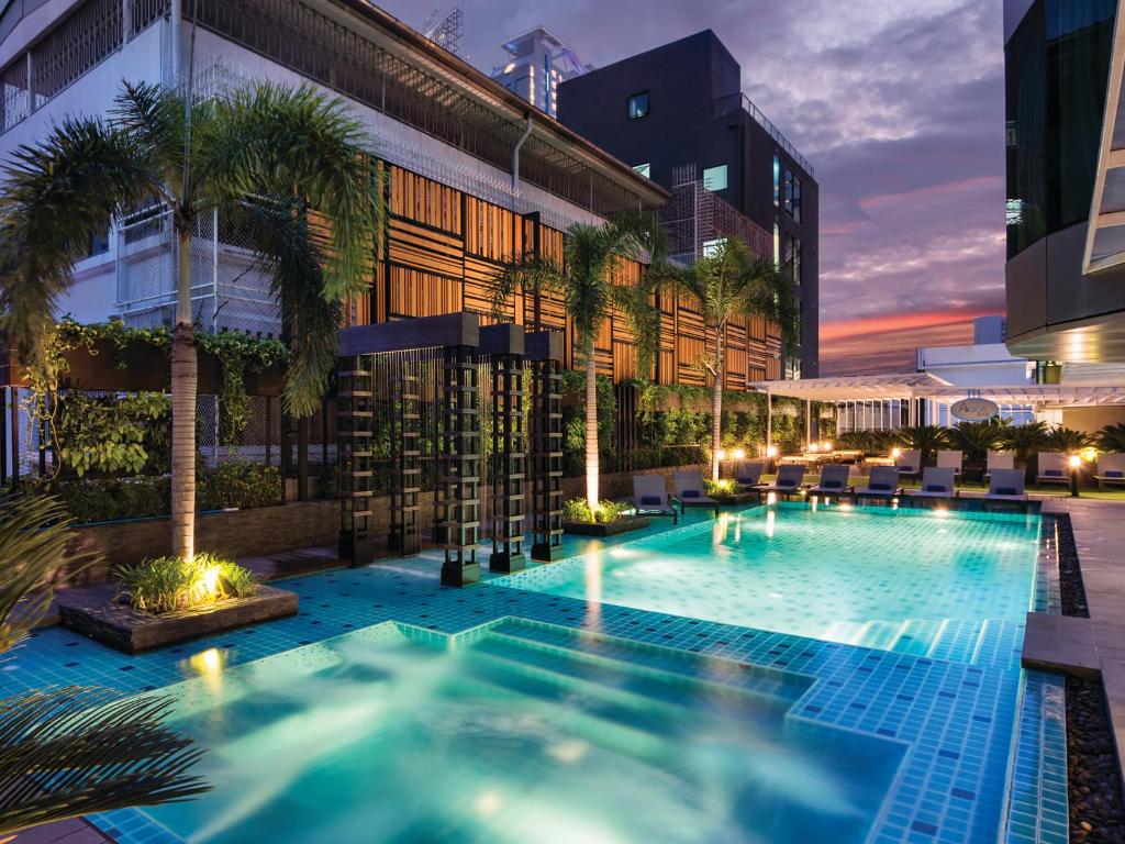 曼谷Solitaire Bangkok Sukhumvit 11的一座楼前棕榈树游泳池