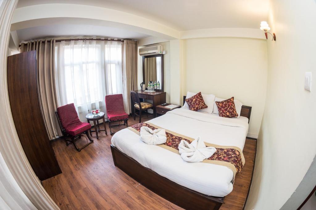 加德满都金座酒店的酒店客房带两张床和一张桌子以及椅子。