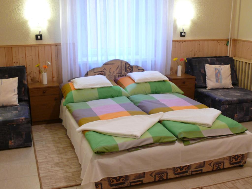 小克勒什Madácsi Vendégház的一间卧室配有一张大床和两把椅子