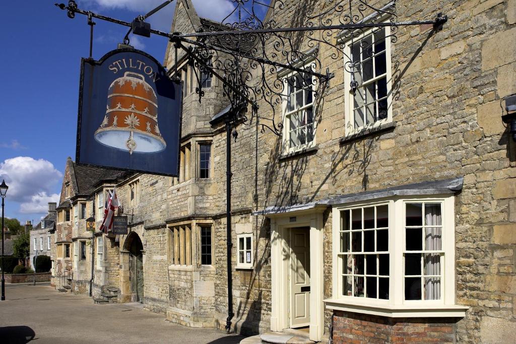 彼得伯勒The Bell Inn, Stilton, Cambridgeshire的一座古老的石头建筑,上面有大标志