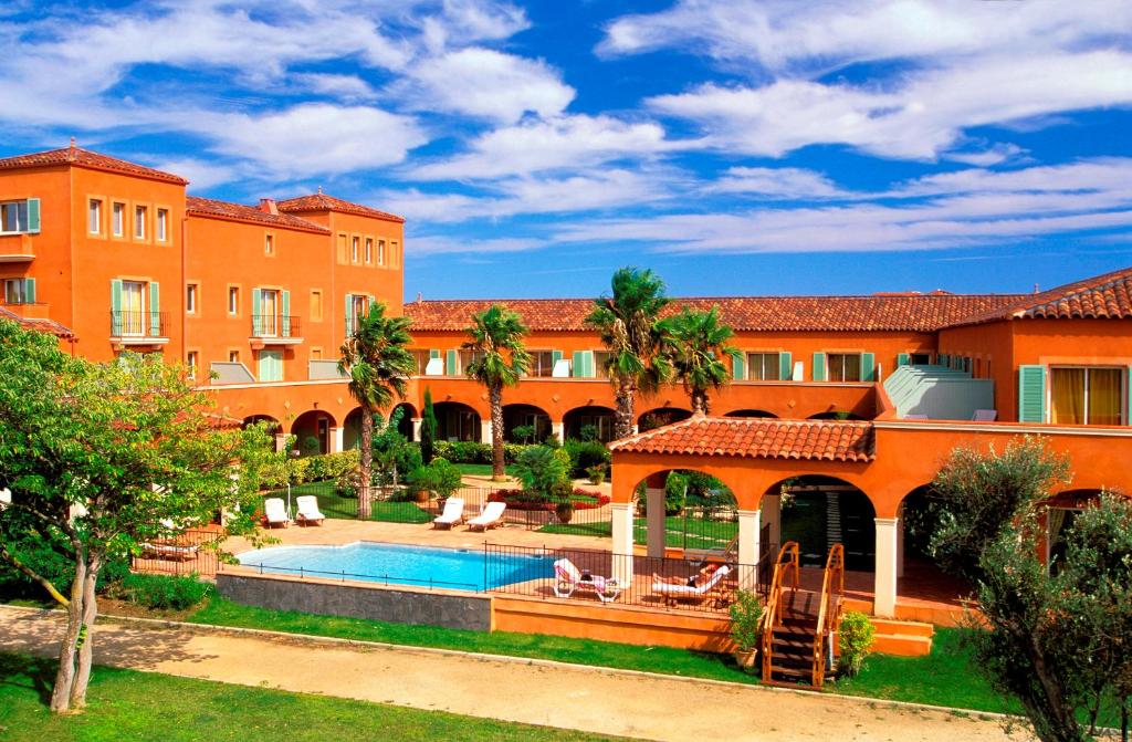 阿格德角巴尔米拉高尔夫及水疗酒店的一座橙色的建筑,设有游泳池和一个度假村