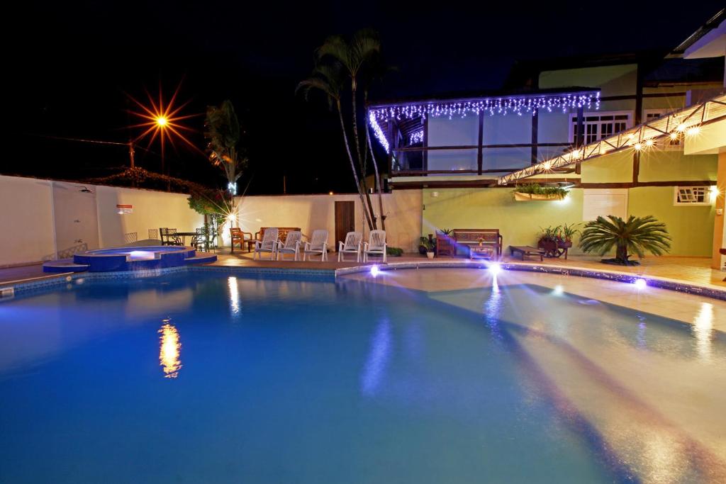伊利亚贝拉Recanto Vicks Flats的夜间大型游泳池,灯光照亮