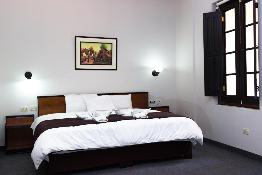 普诺科罗尼尔广场酒店的一间卧室配有一张带白色床单的大床
