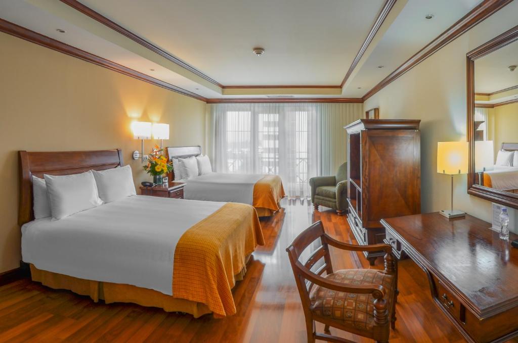 危地马拉瓜地马拉卡萨维兰达酒店的酒店客房设有两张床、一张桌子和一台电视。