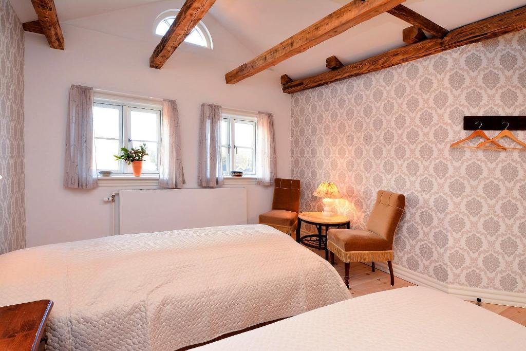 Øster AsselsStrømpehuset的一间卧室配有两张床和一张桌子及椅子