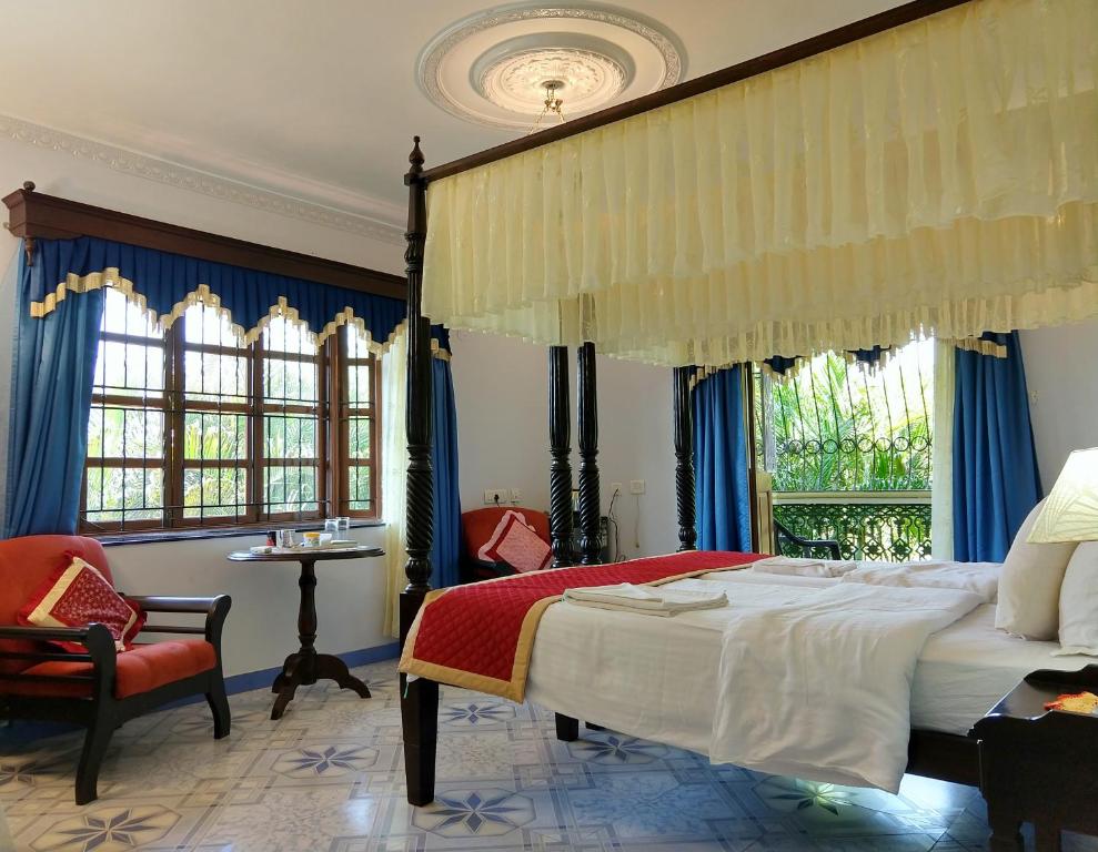 比纳里姆Palm Grove Cottages - Leisure Resort的一间卧室配有一张床、一把椅子和窗户。
