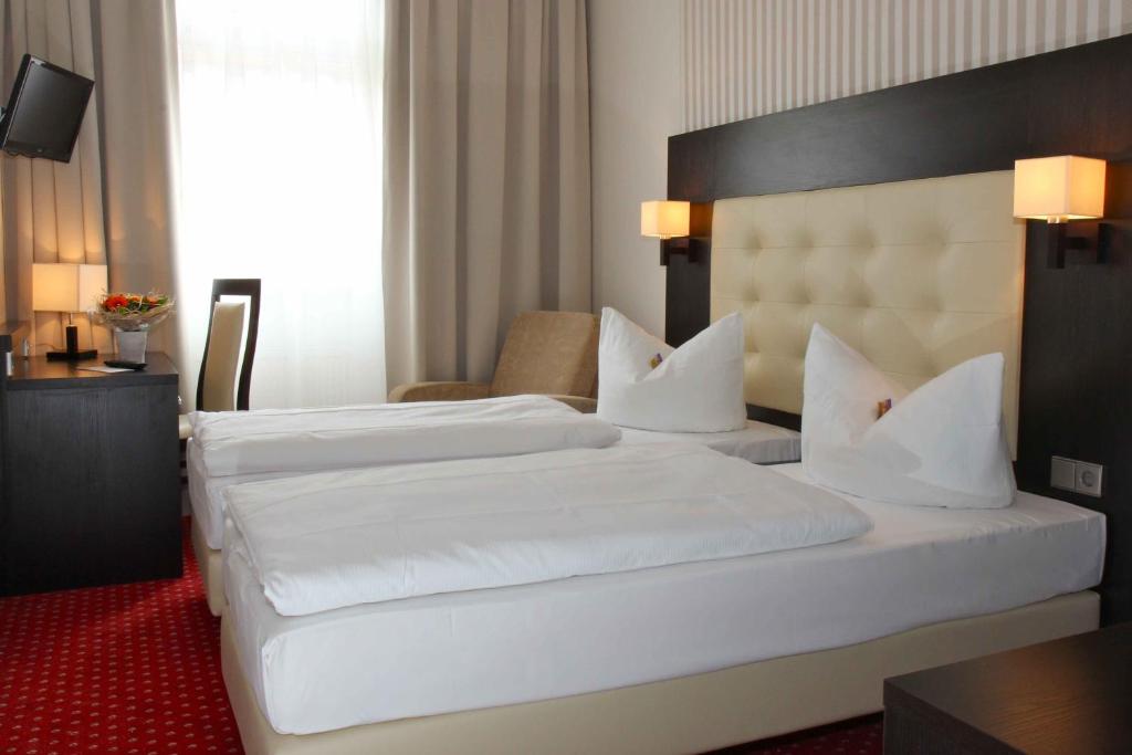柏林斯特柏林酒店的配有白色床单的酒店客房内的两张床