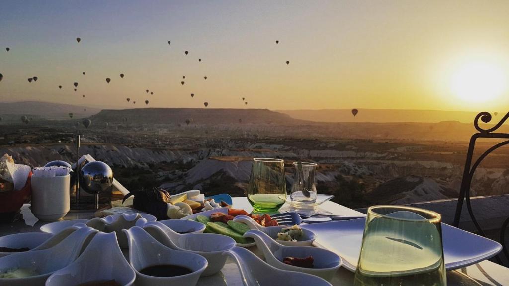 乌奇希萨尔卡帕多西亚之眼洞穴酒店的一张桌子,上面放着一盘食物,还有日落