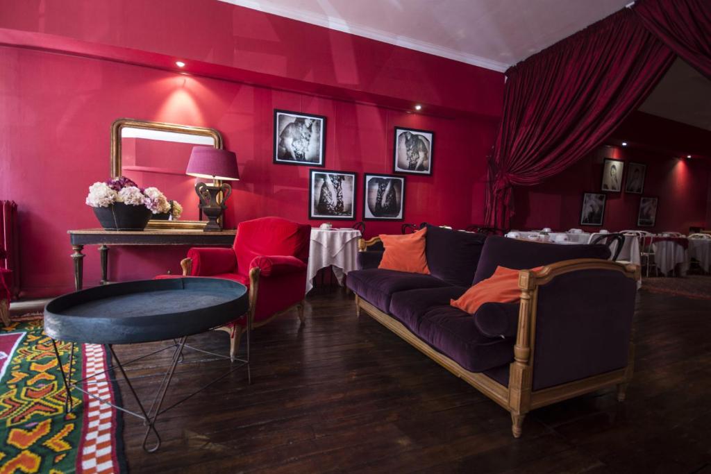 昂古莱姆帕莱斯酒店的客厅设有红色的墙壁、一张沙发和一张桌子